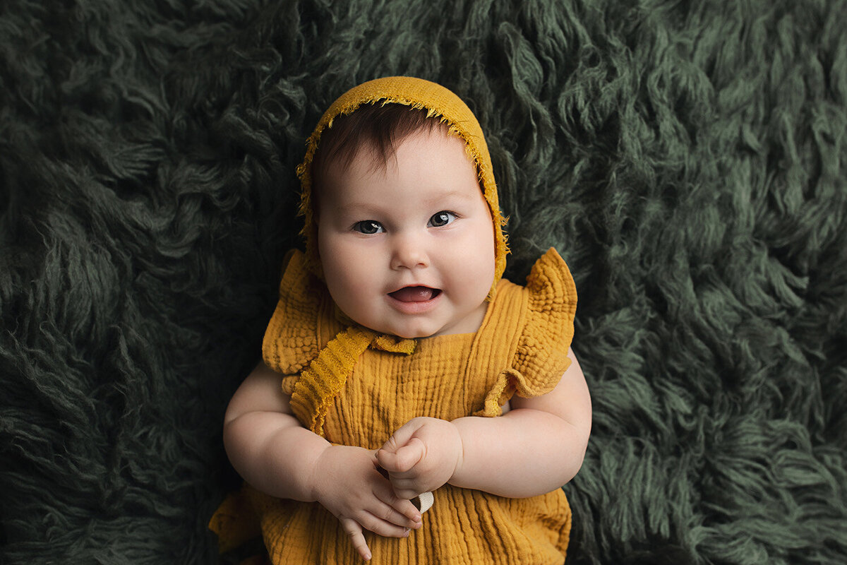 smiling baby in gold  lying on blanket