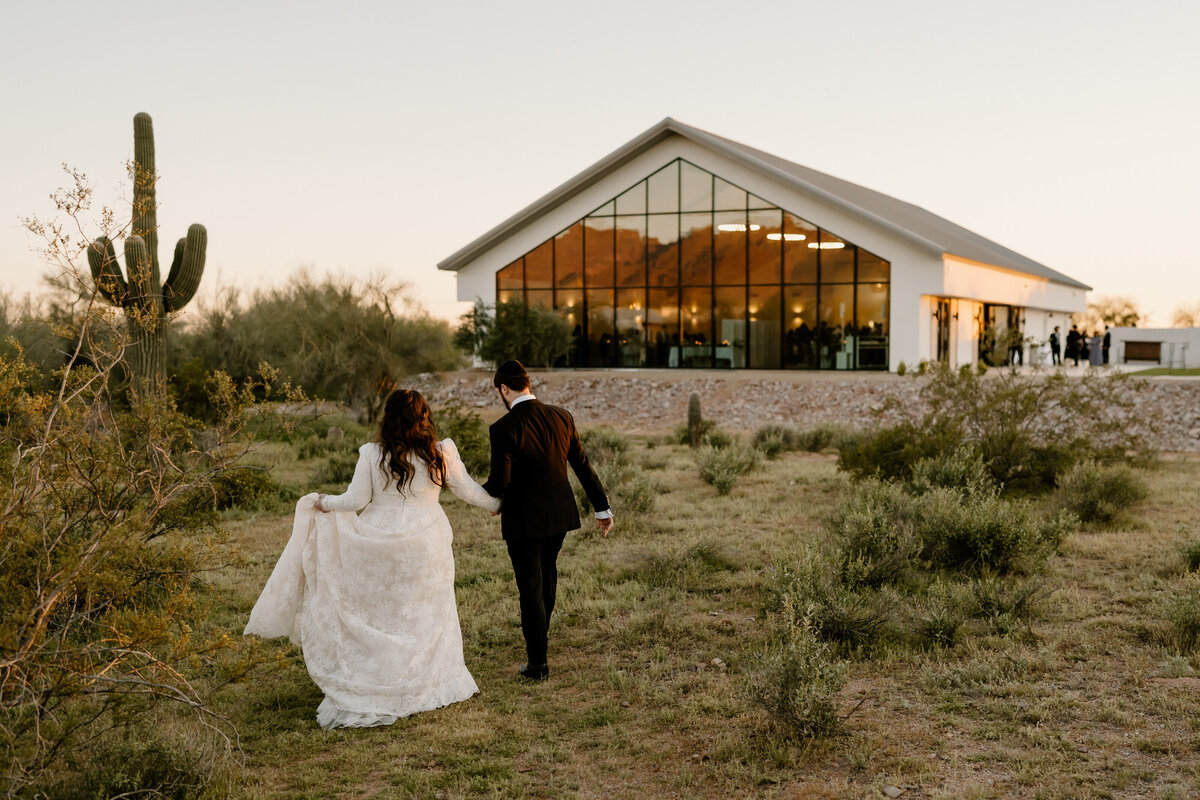 Bride and groom walking in the desert toward the wedding venue