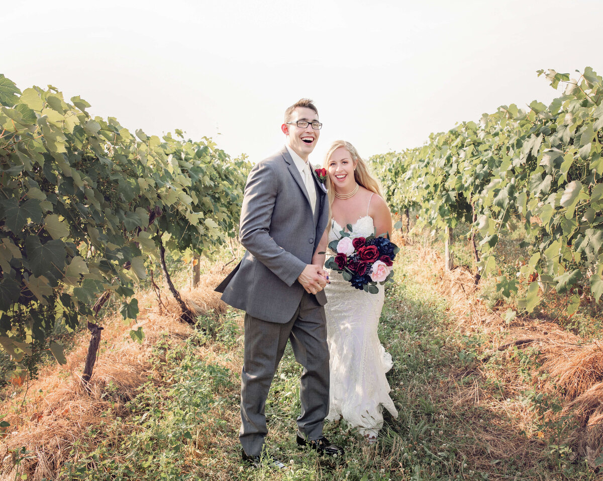 Portrait of a bride and groom walking through a vineyard