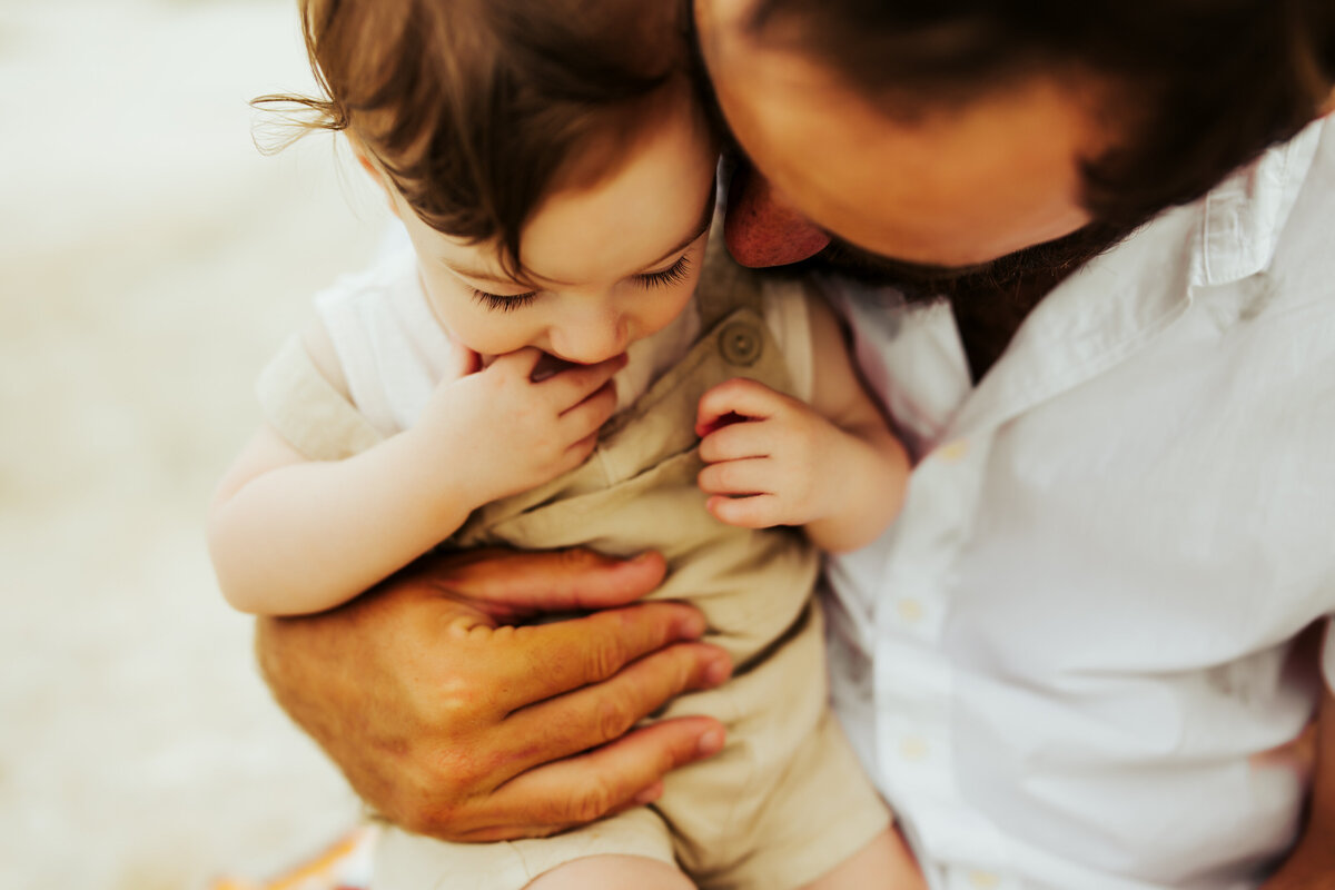 a father and son cuddling at the beach during a retro inspired family session