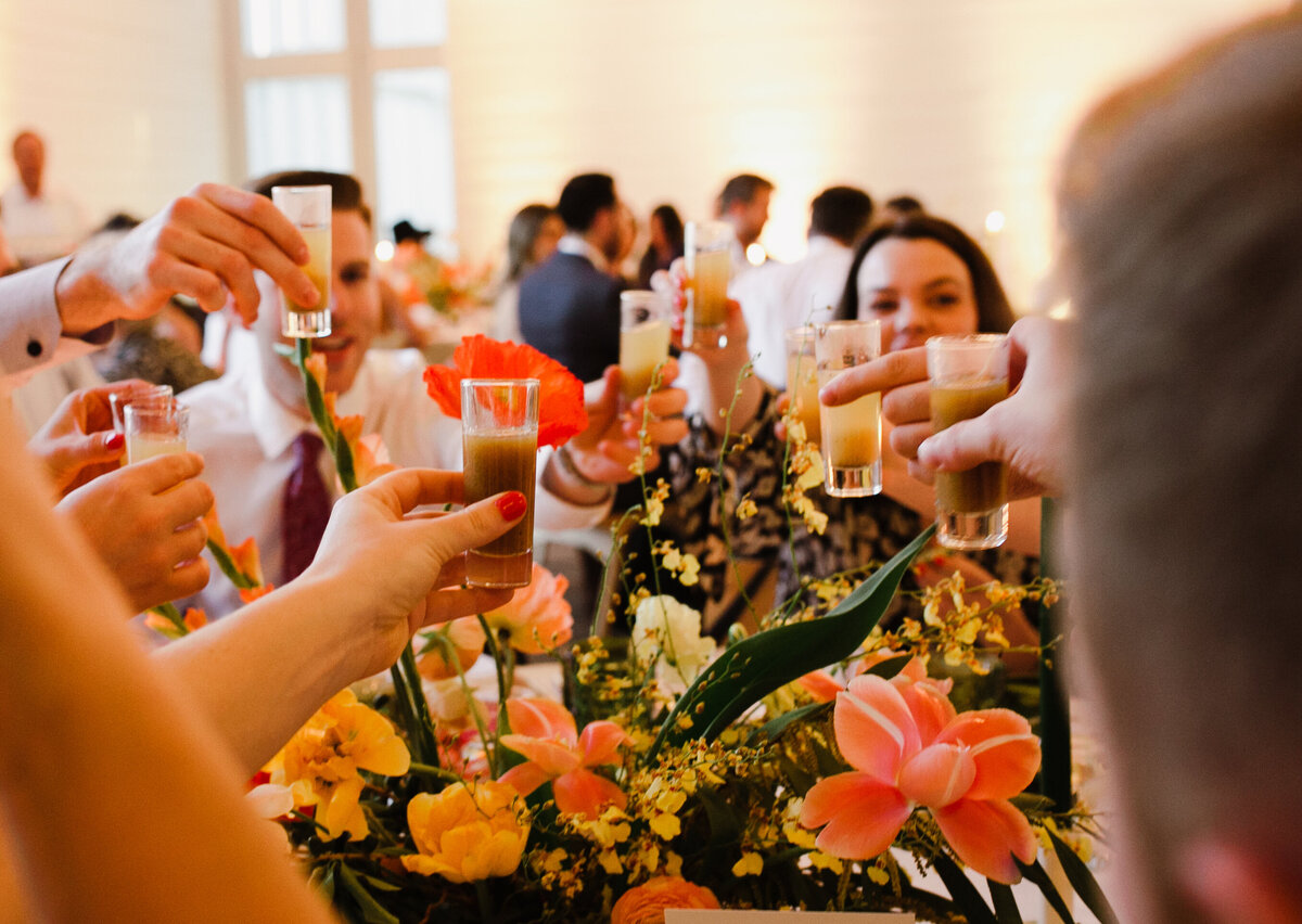 Guests toasting with drinks at Wedding reception with yellow florals at Prospect House wedding Austin