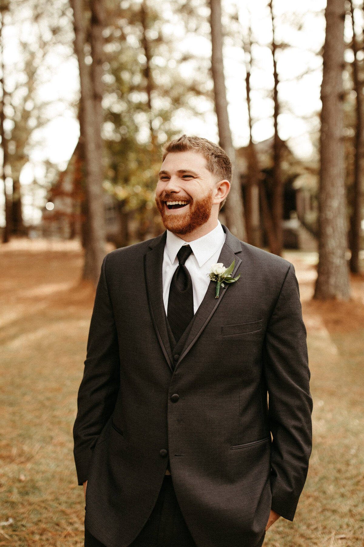 Groom in grey suit and simple greenery boutonniere smiling