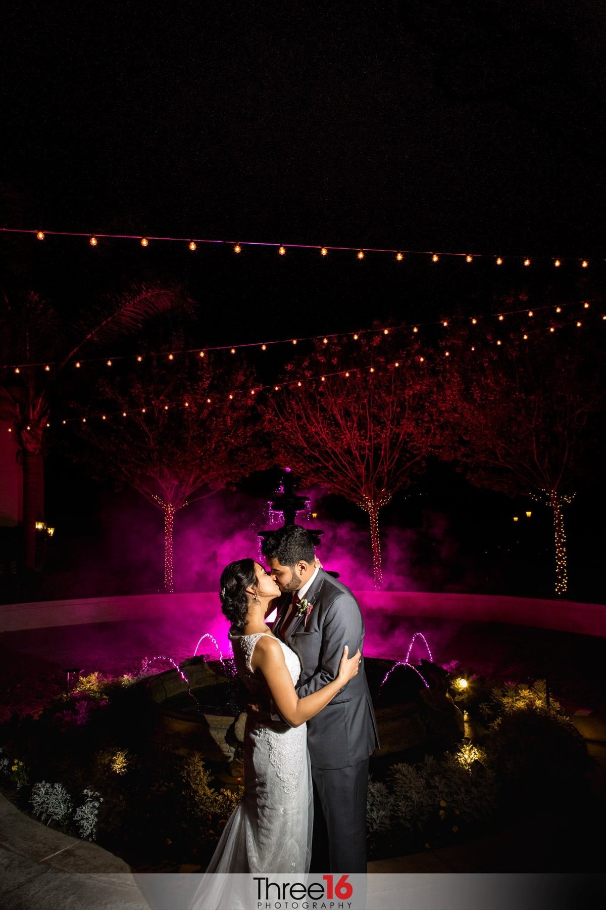 Bride and Groom share a kiss late into the evening with purple haze background