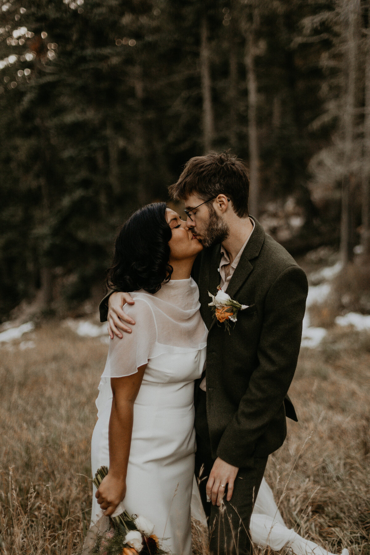 bride and groom holding each other on a mountain slope in NM