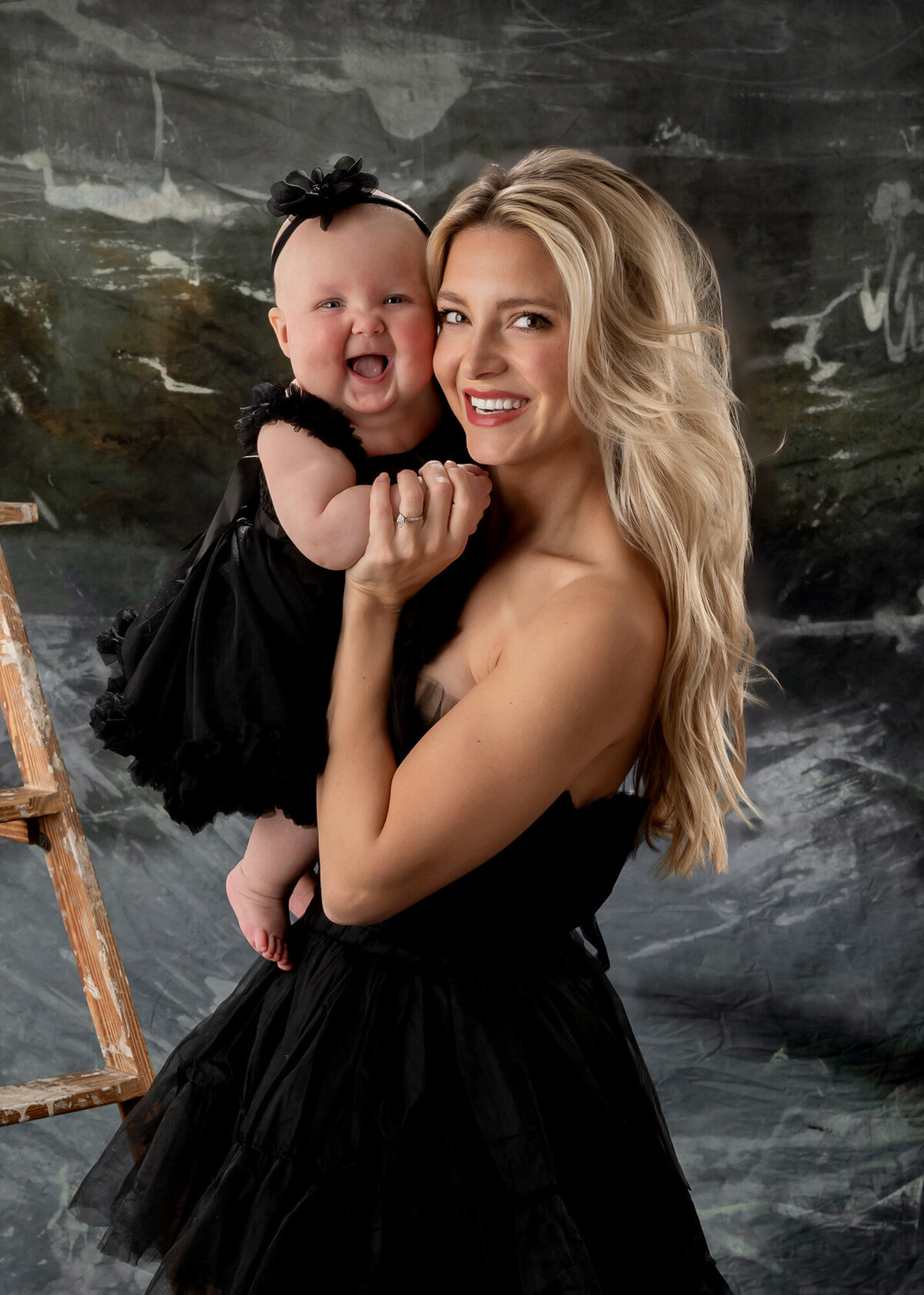Mom holds her baby girl while they both smile big