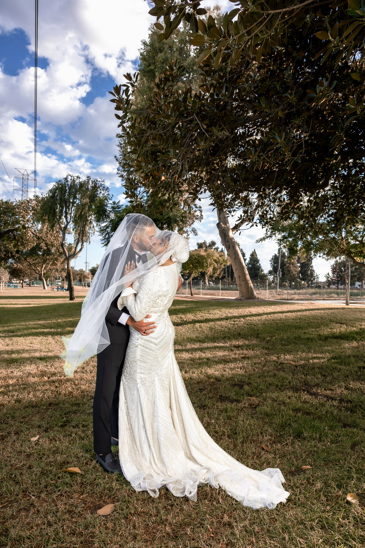 Bride and Groom Sharing a Soft Kiss Under Veil – LA Arabian Wedding Portrait