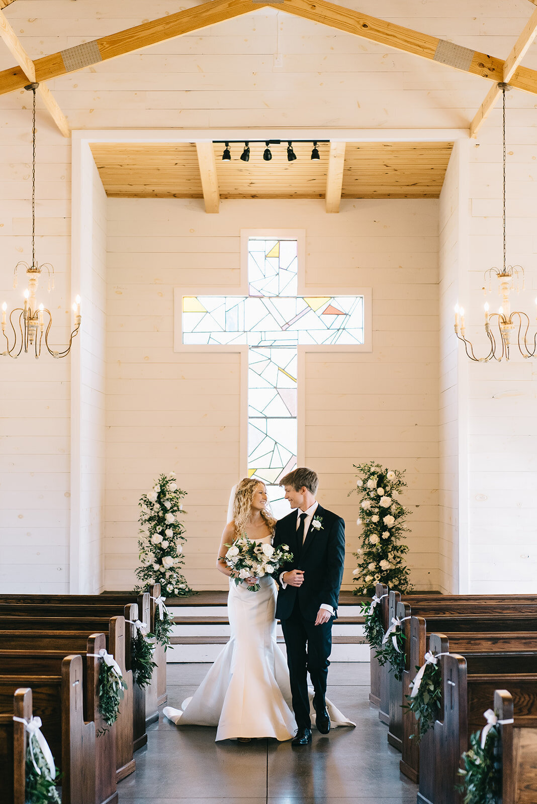 Bride and groom walking down aisle with white and green altar florals designed by Abby Grace Florals at Saluda SC wedding