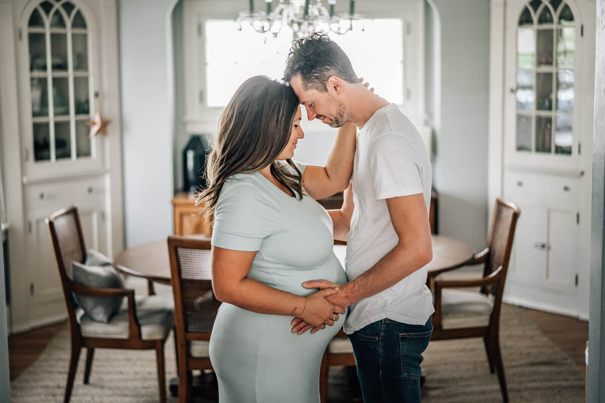 An expecting couple embraces romantically  in their home during a maternity photoshoot.