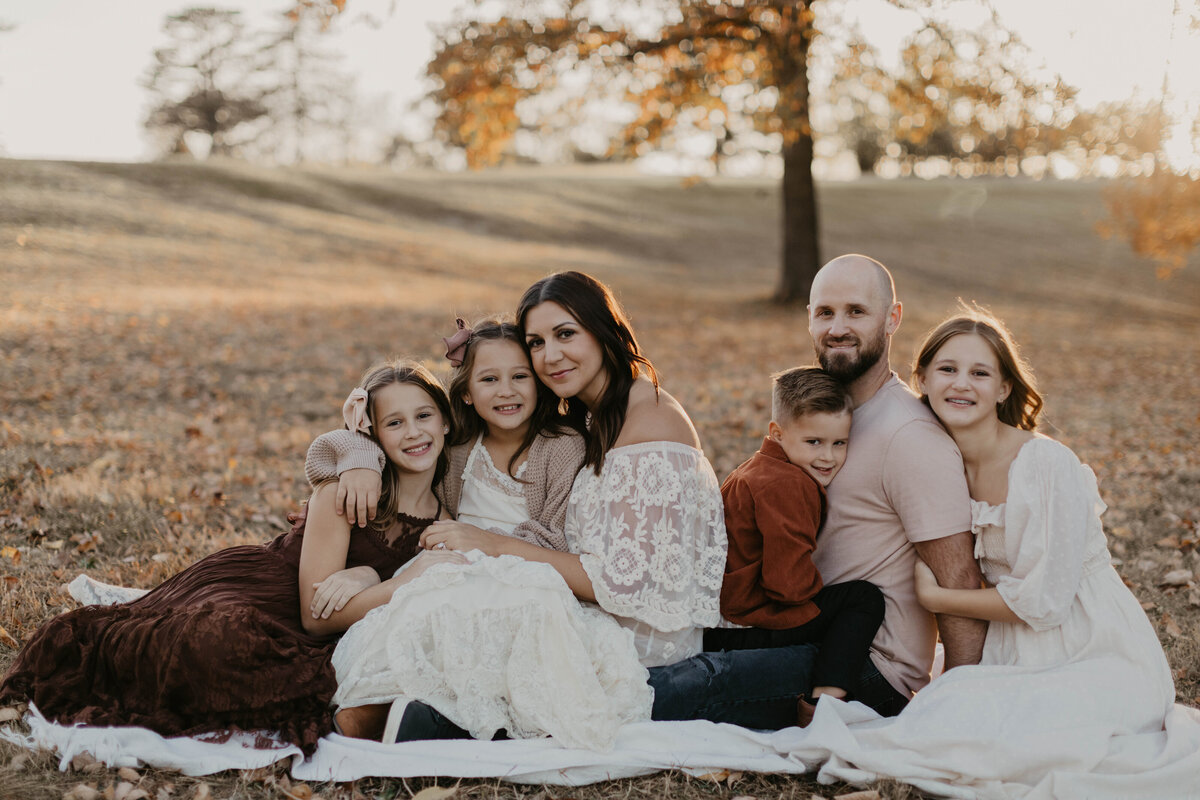 Family of 6 sitting together hugging one another. 