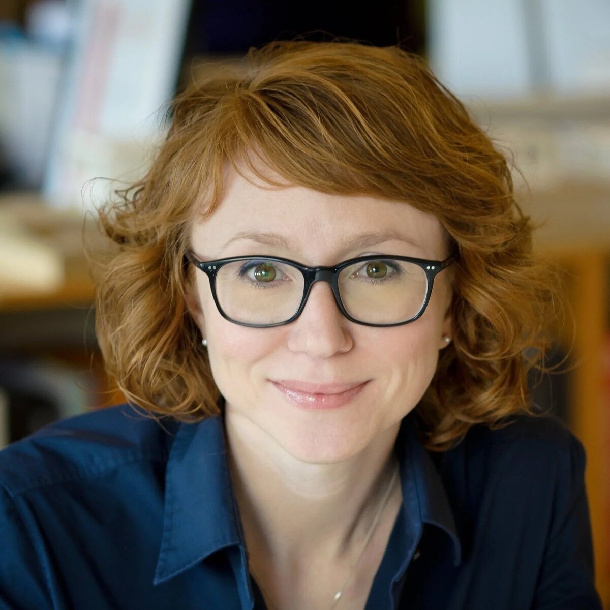 NJ professional headshot of woman with glasses smiling in office background
