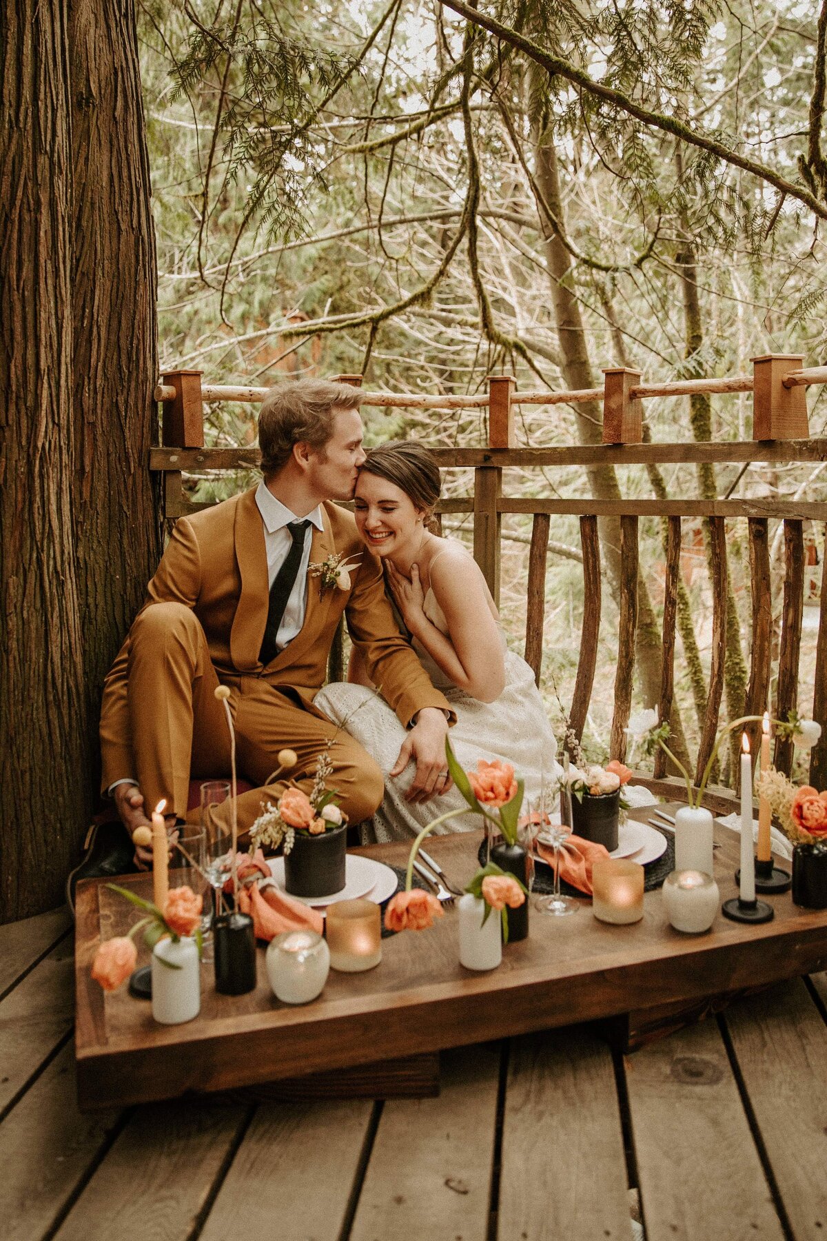 Bride & groom sitting down to elopement picnic on tree deck!
