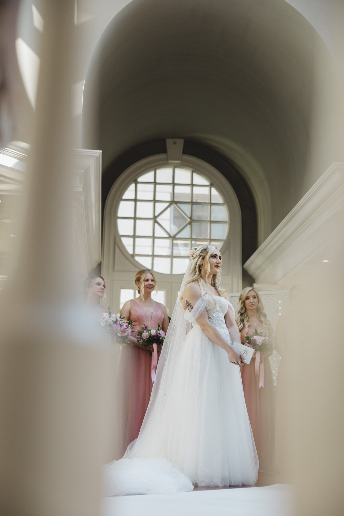 View from below of a person in a wedding dress with their wedding party behind them 