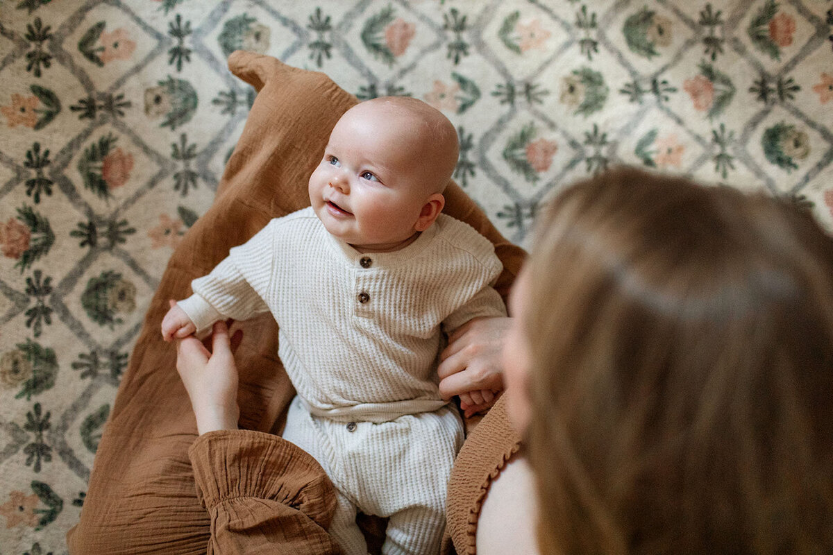 New mother cradling newborn baby - Sara James San Antonio newborn photographer specializes in capturing precious maternal bonds and fresh parent-infant connections during peaceful home portrait sessions