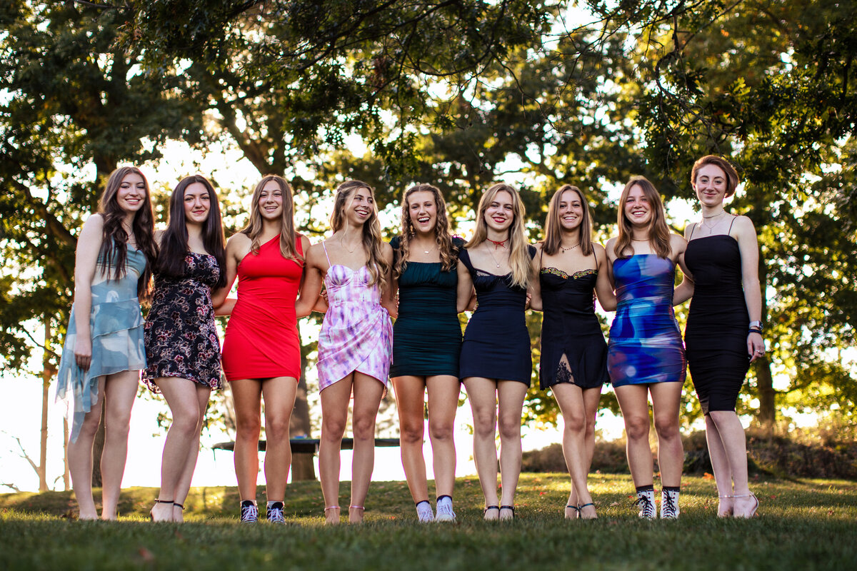 A group of senior girls walks linking arms in a field for their last homecoming of the season