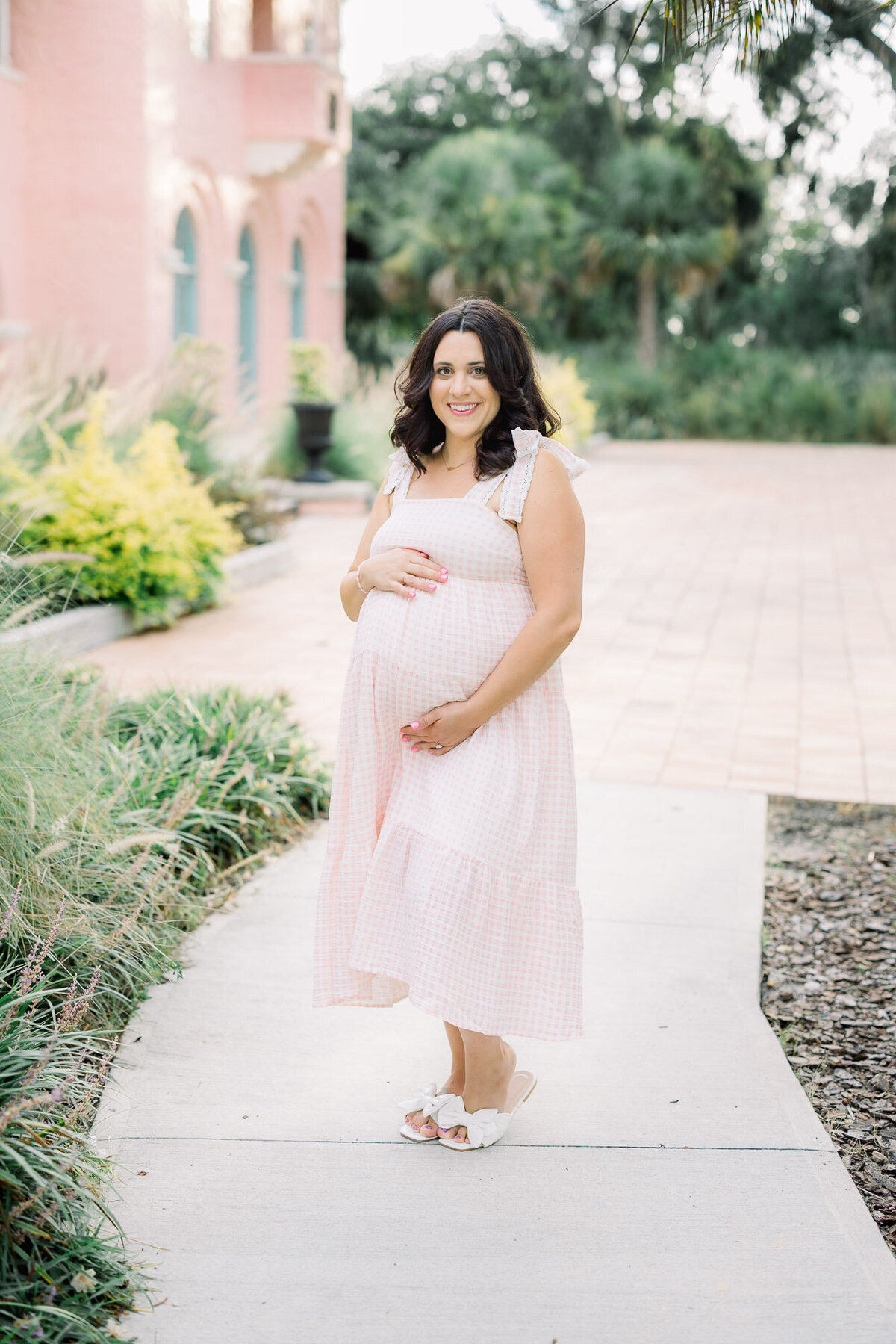Pregnant woman wearing a pink dress for Tampa maternity photographer Tina Marie Studio.