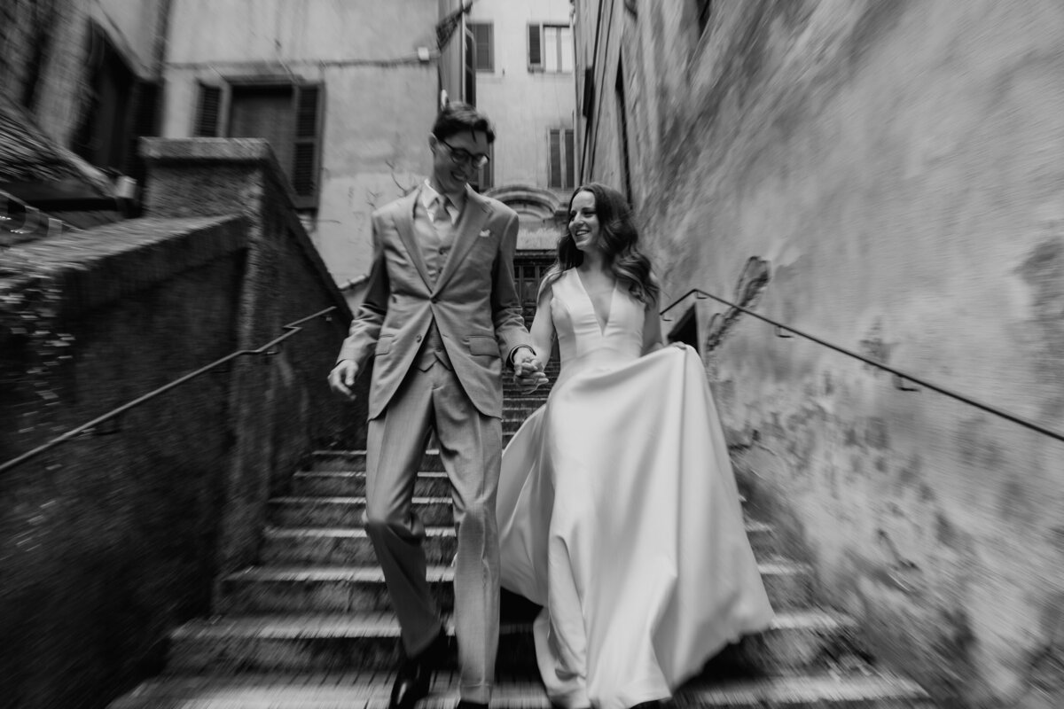 Couple standing on stone staircase in narrow Roman alley.