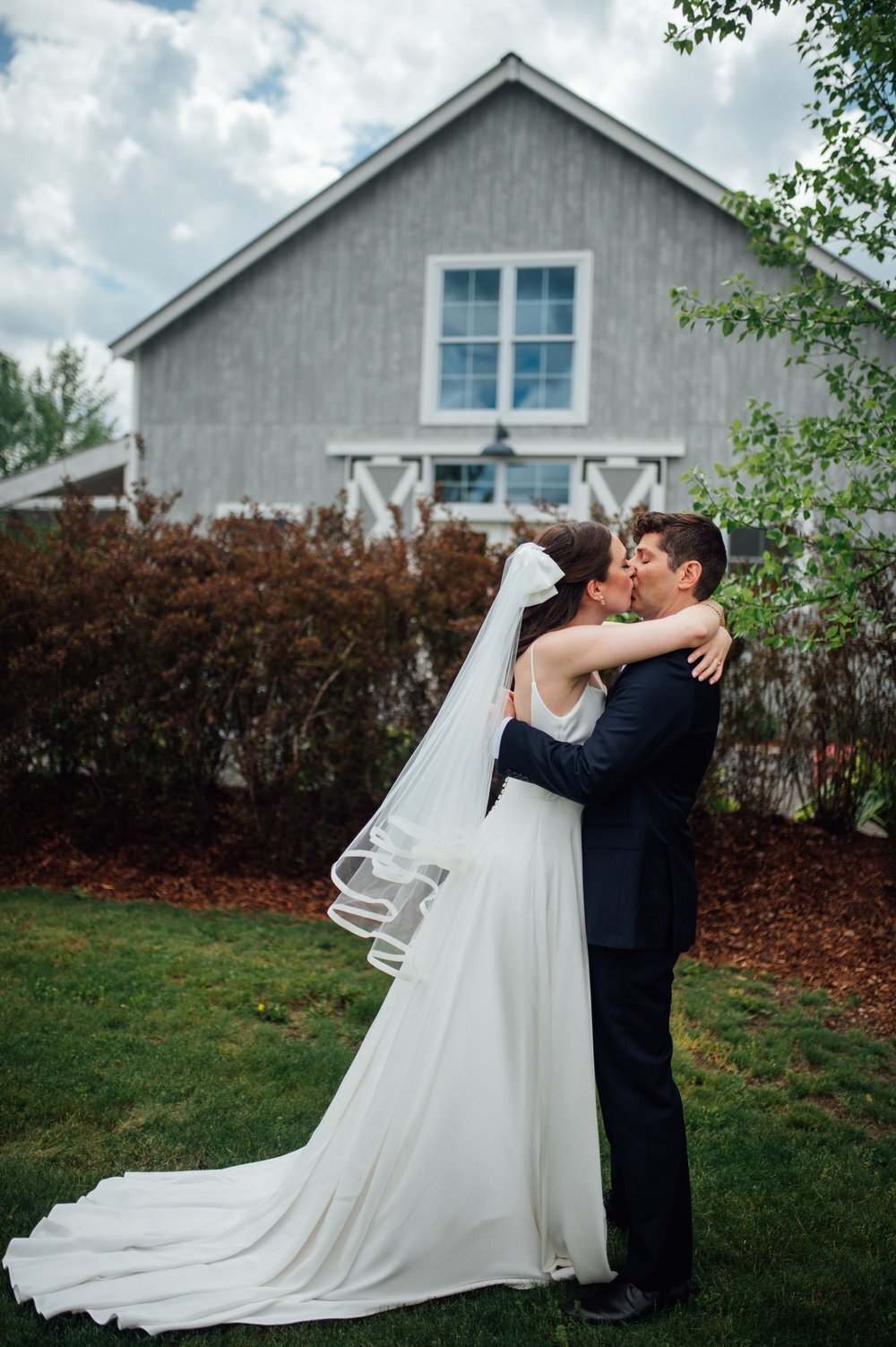 bride and groom kiss in front of the barn at smuggs in stowe vermont