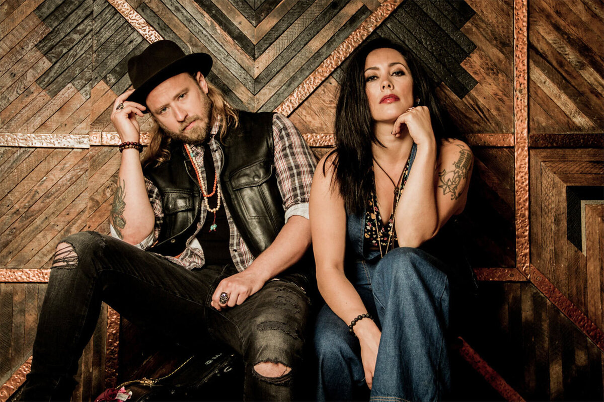 Country Music Duo Portrait Sons of Daughters seated in front of wood patterned wall