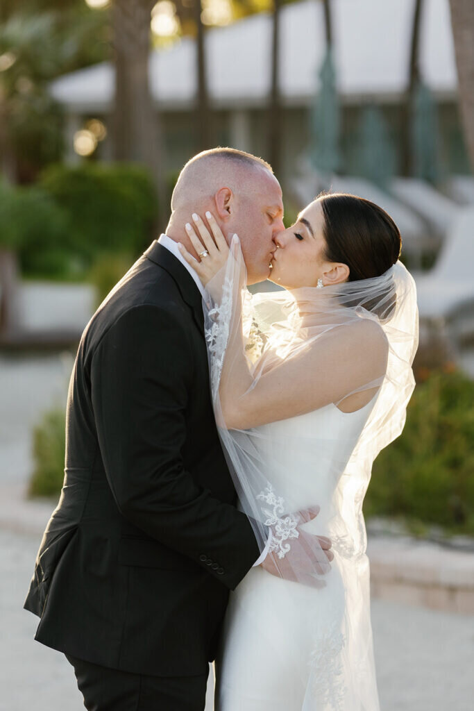 An intimate and artistic portrait of the newlyweds kissing under the bride’s veil, bathed in soft golden light. Florida Keys wedding photography by Claudia Amalia Photography.