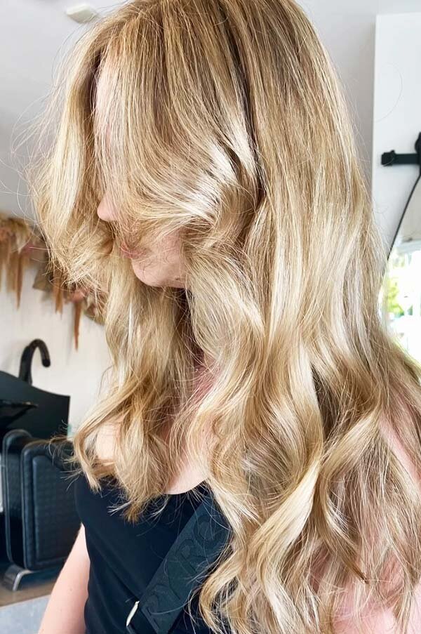 Bouncy blonde waves with a luminous finish, showcasing premium salon hair colouring and blowdry services at Blake & Kwan Hairdressing.