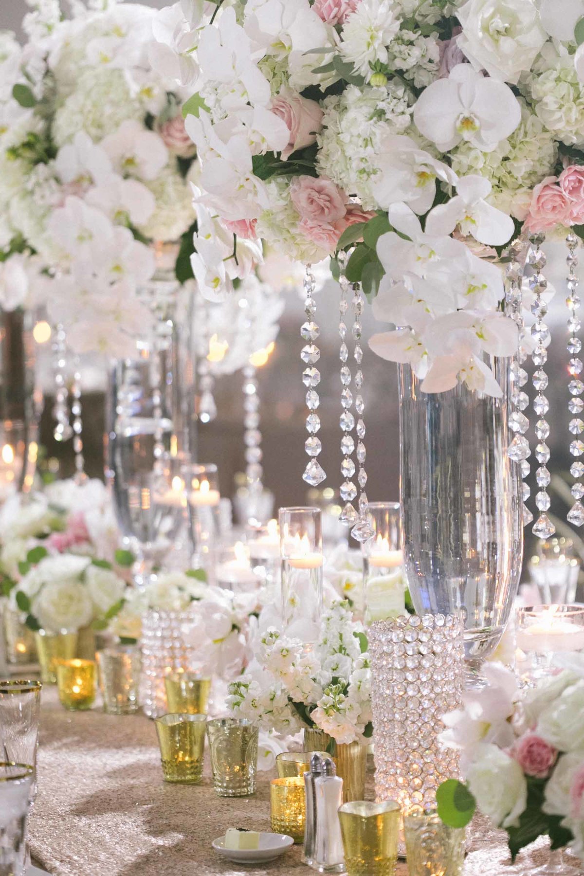 Stunning wedding reception table, tall arrangements with phalaenopsis orchids and crystal strands.