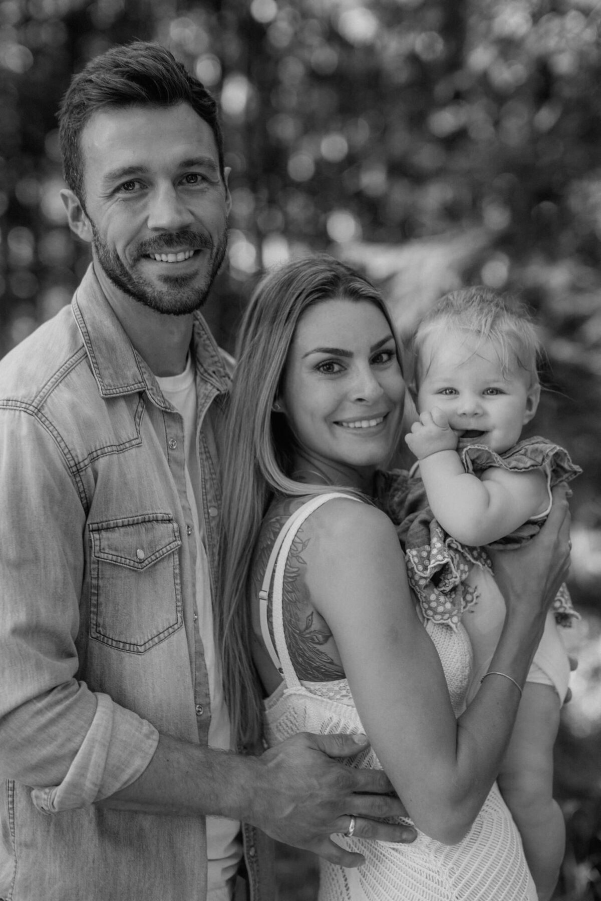 Mom holds the babygirl, dad hugs mom.