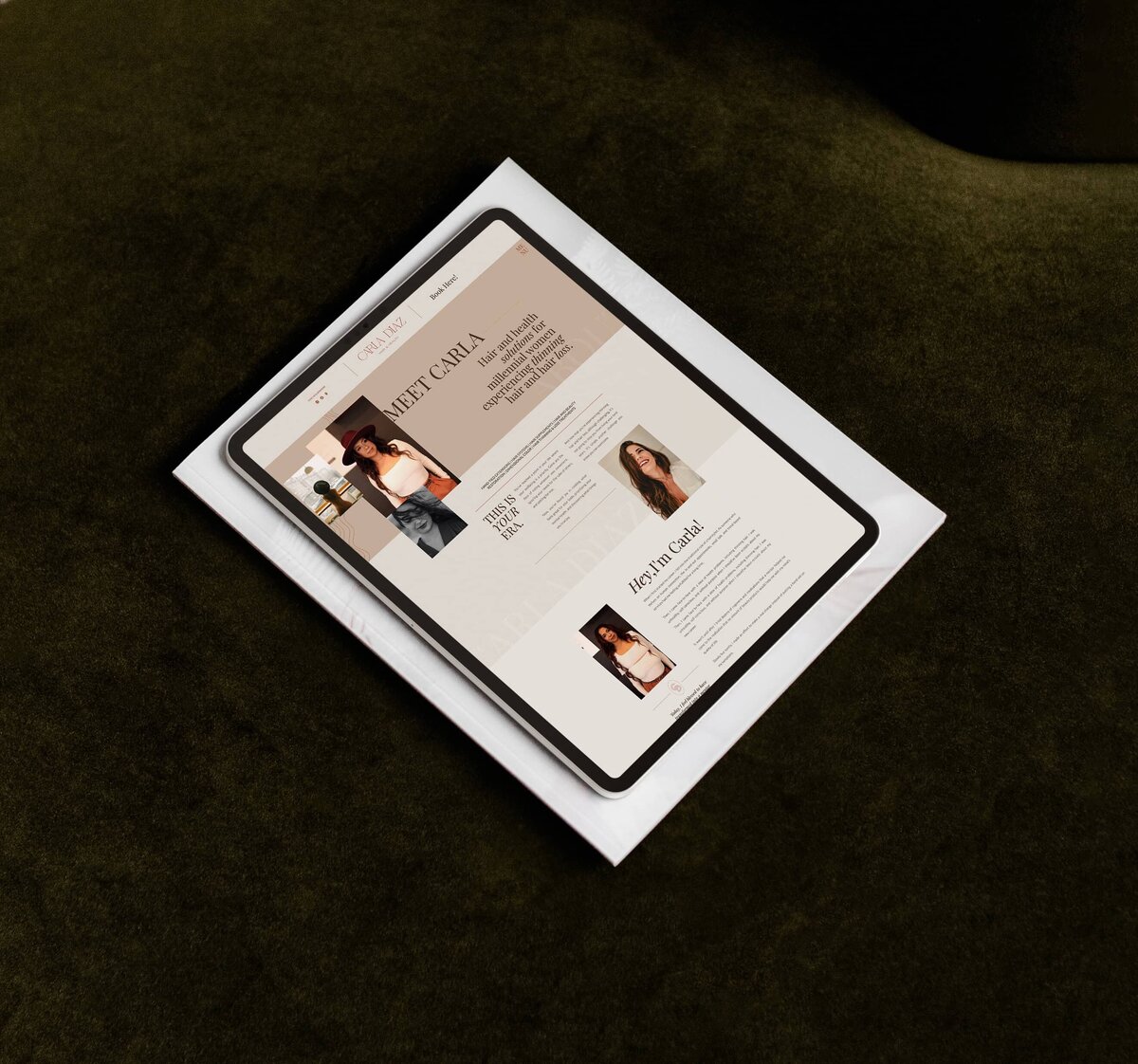 A tablet displaying a webpage with the title "MEET CARLA" lies on a white book atop a dark green surface. The webpage, showcasing Carla's branding and Showit web design for salons, features text and images of a woman.