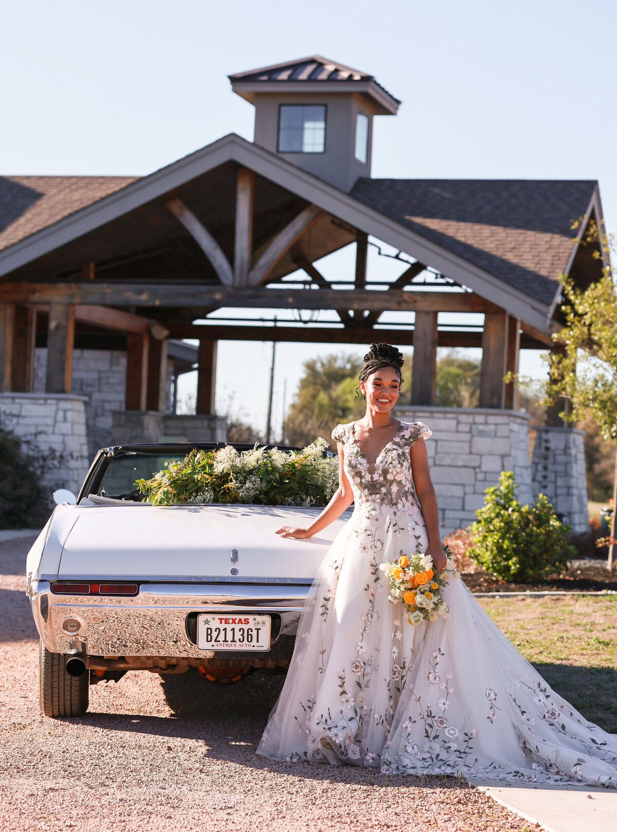 bride wearing floral dress and standing in front of vintage car at High Pointe Estate in Austin Texas by Austin Texas Wedding Photographer Amanda Richardson Photography