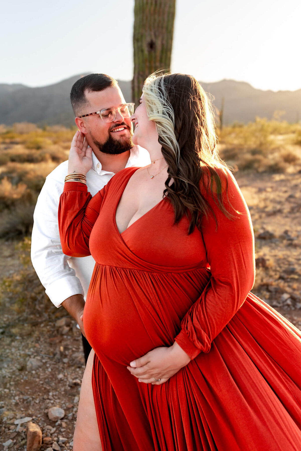 Expecting wife leaning into husband and softly pulling him in for a kiss. 