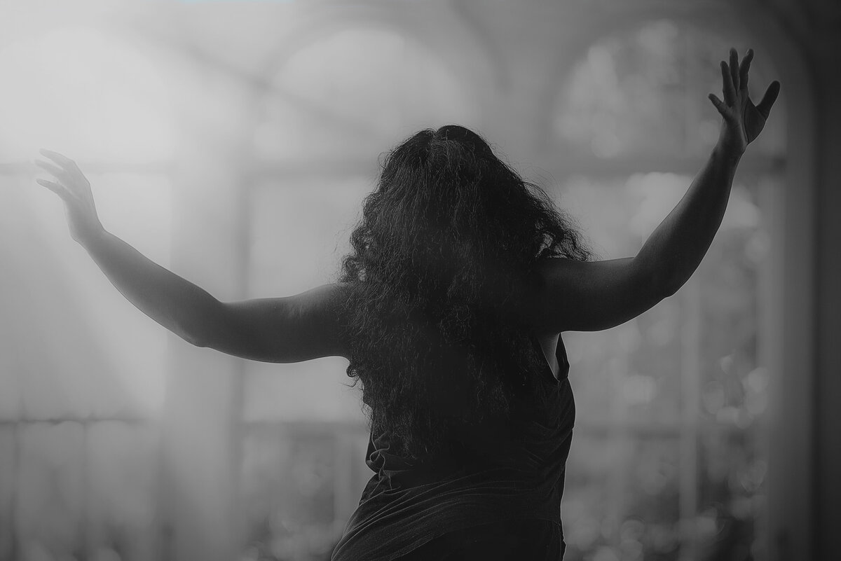 A black and white photo of a person with both of their arms outstretched