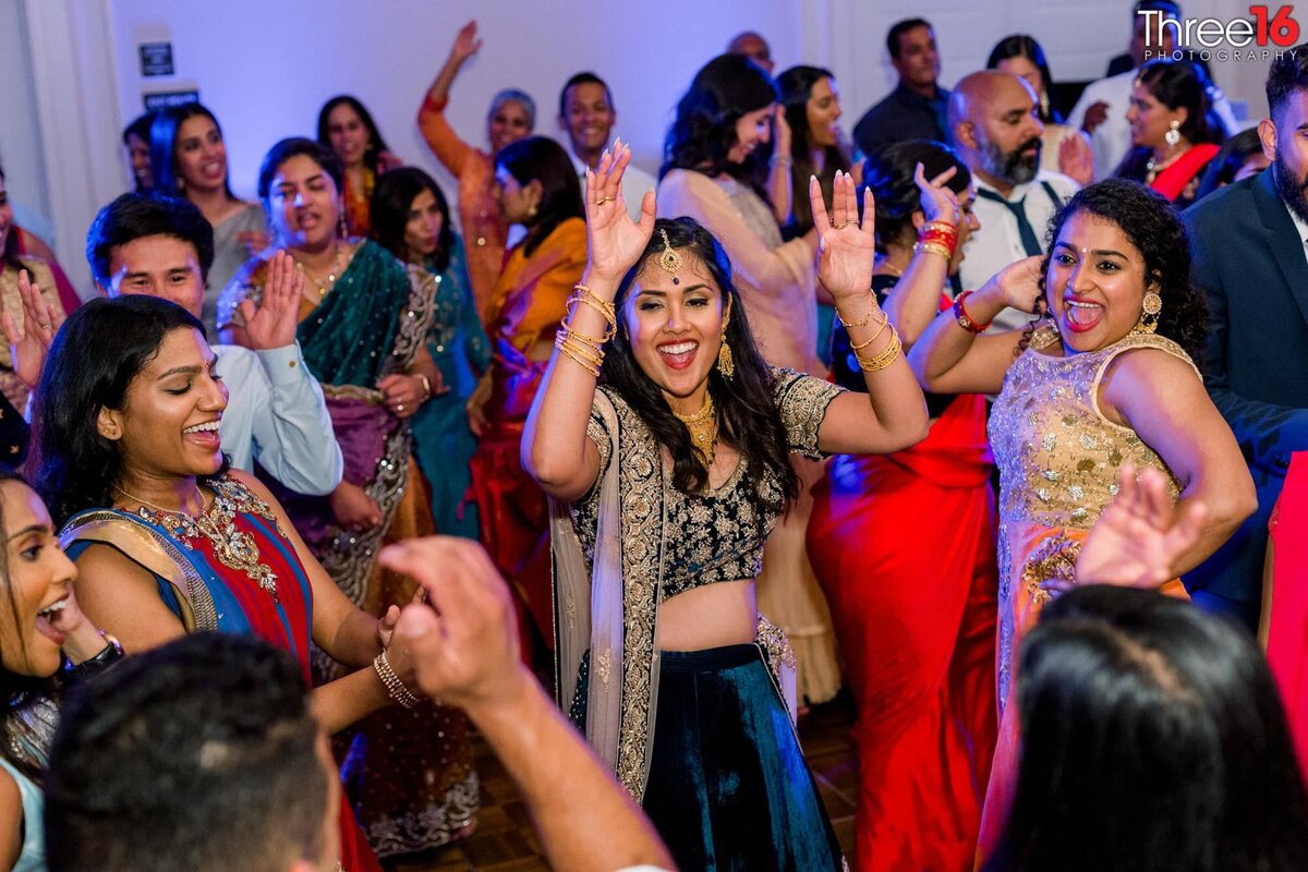 Bride smiles as she dances with her bridesmaids