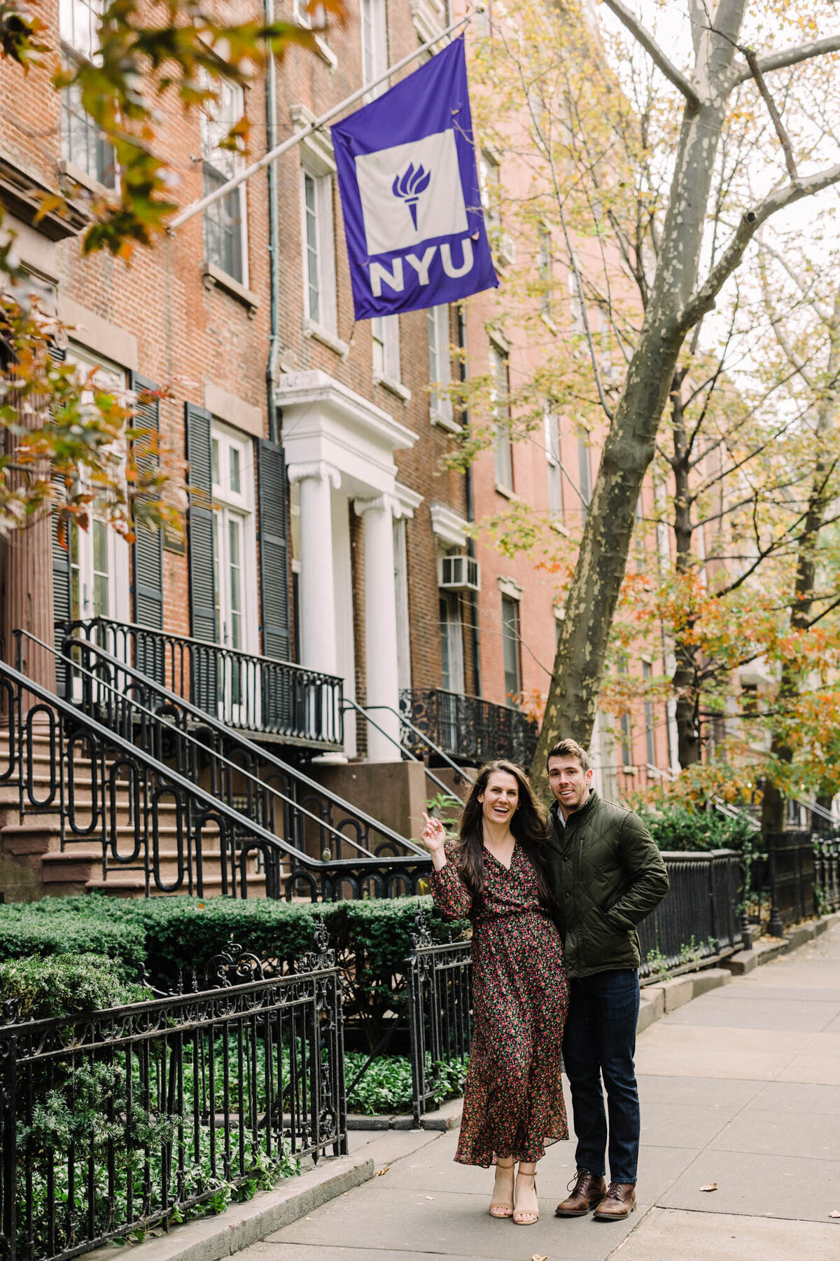 NYU Alumni pose under college banner for engagement photo