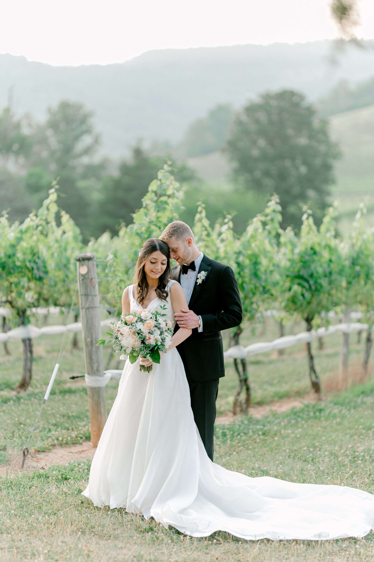 Groom nuzzling to his bride in a picturesque vineyard located in Leesburg, Virginia