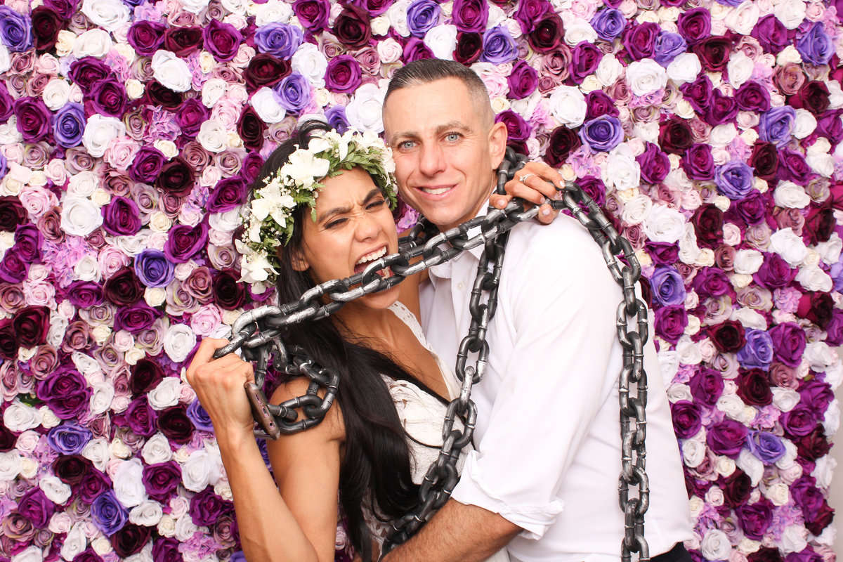 Bride and Groom are all in chains in a photo booth rental from Three16 Photography