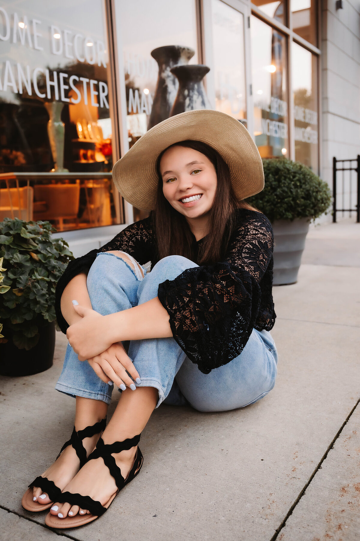 This senior sits on a sidewalk in downtown Coralville for her senior photos.