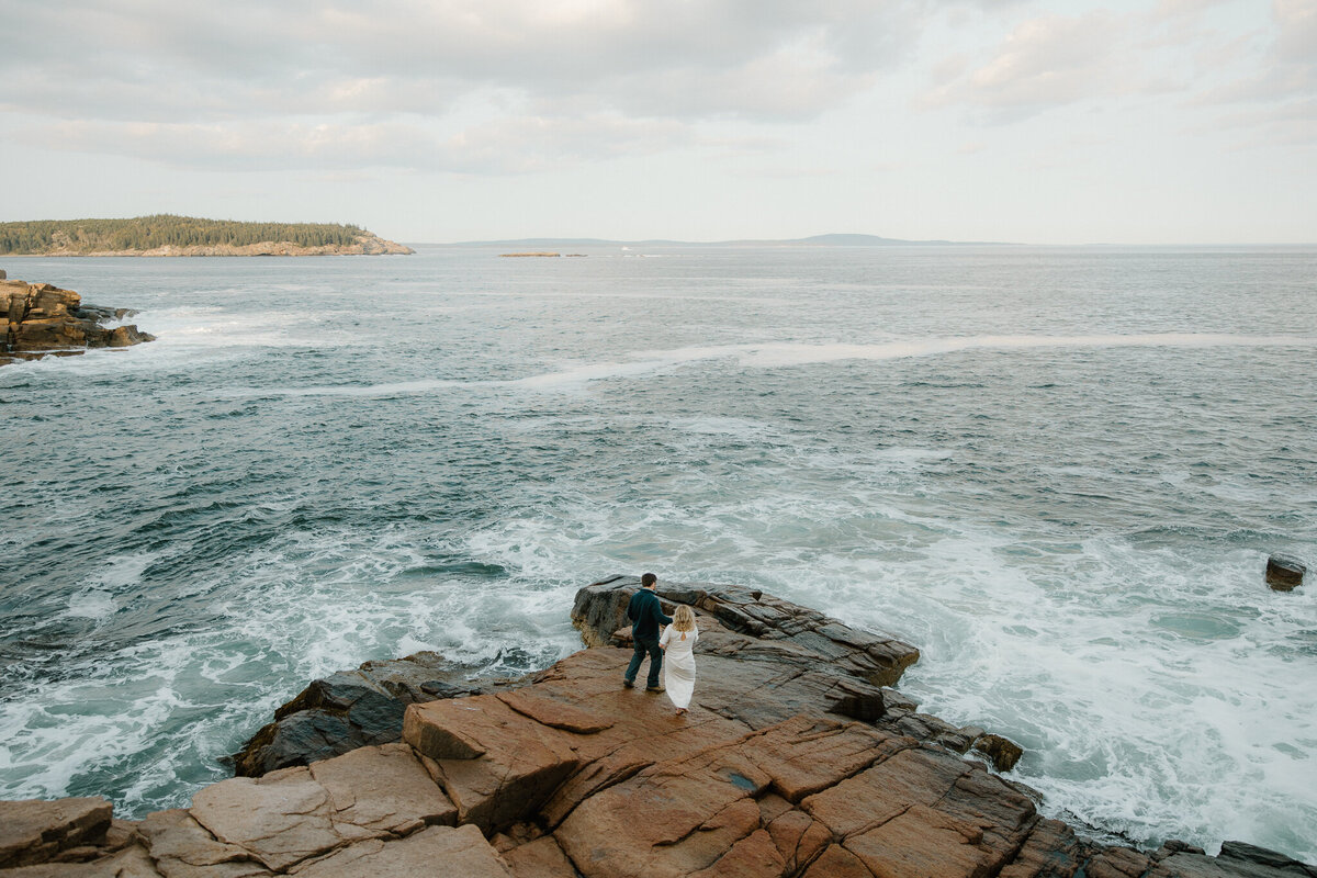 A couple walks out onto the cliffs of Acadia