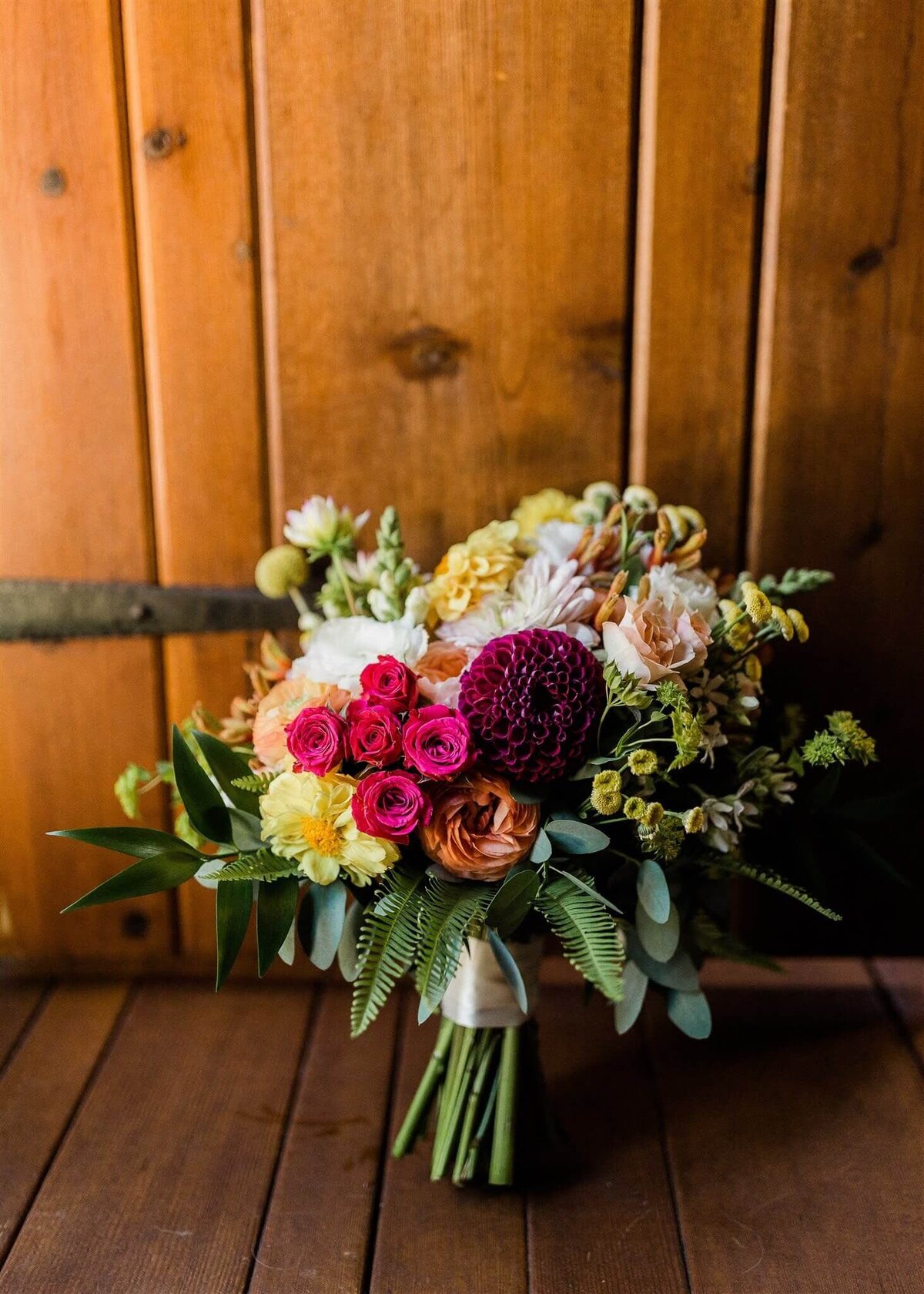 Bright summer bouquet with fern and dahlia amongst other flowers.
