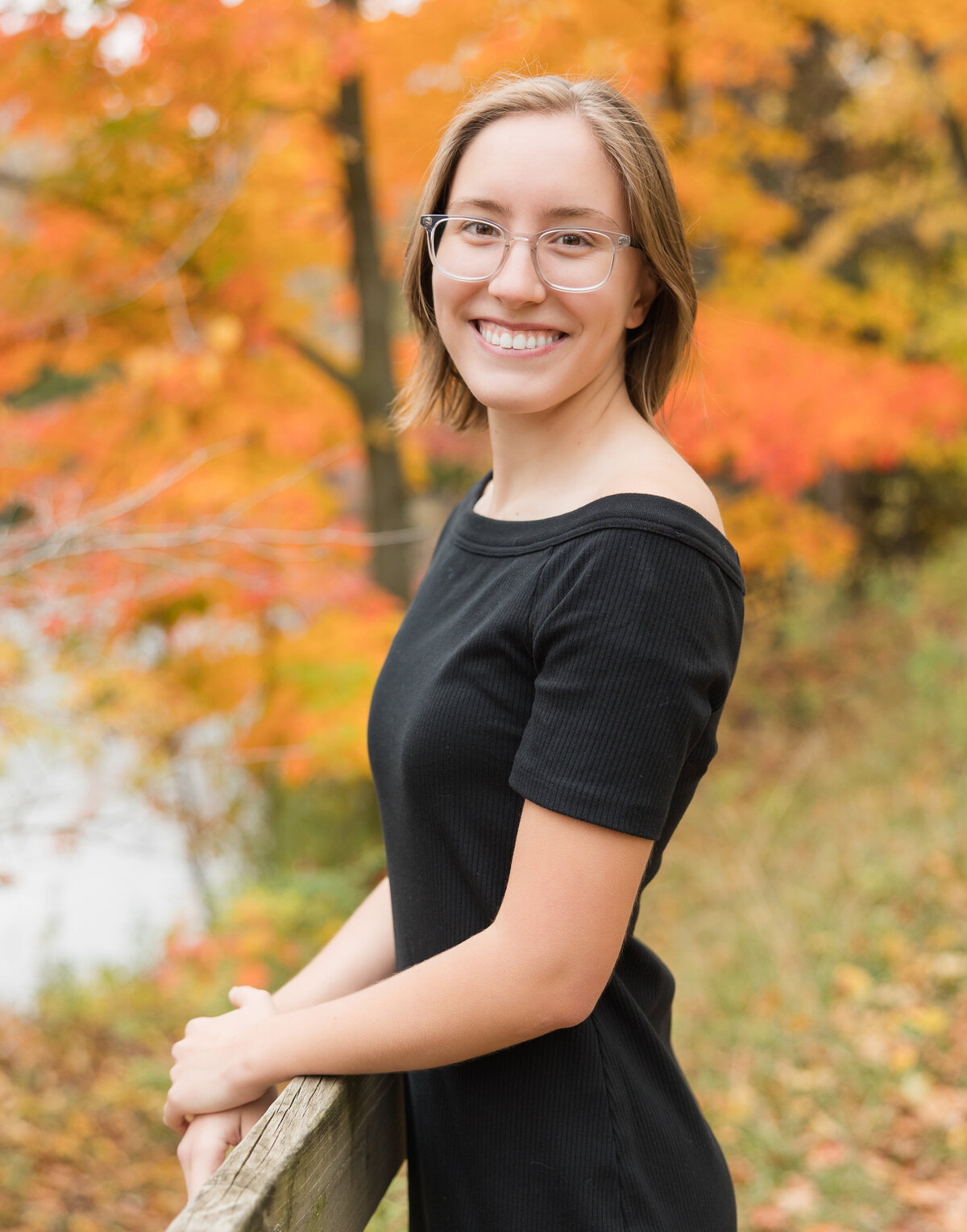 Senior girl standing by a rail smiling at the camera