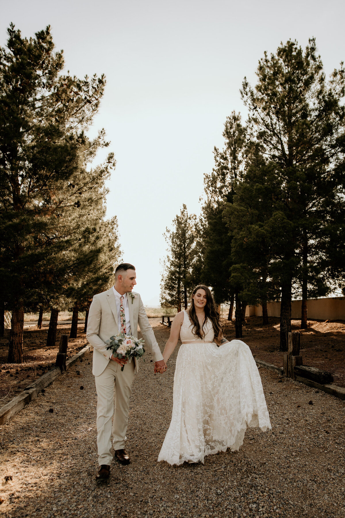 newlyweds walking together through trees in the desert