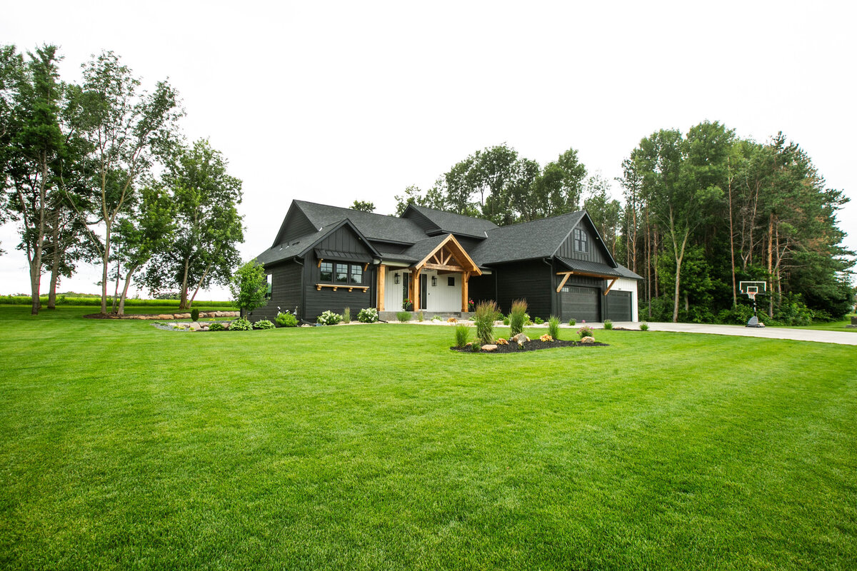 Exterior view of custom home in Otsego, Minnesota with modern wood details and front porch built by Cornerstone Custom Builds