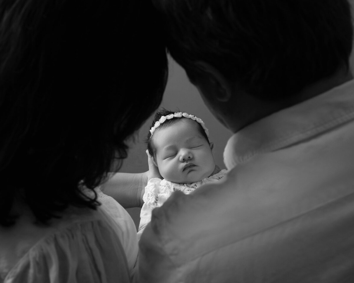 parents looking at newborn baby black white photo