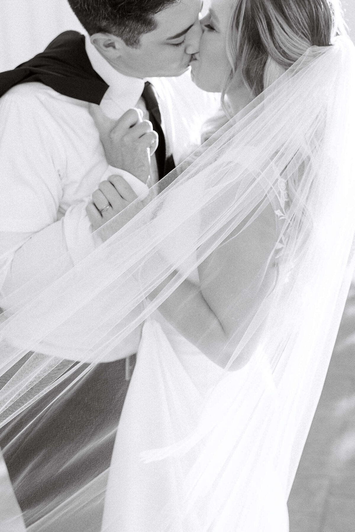 Newly married couple kisses while wrapped in veil at North Texas wedding