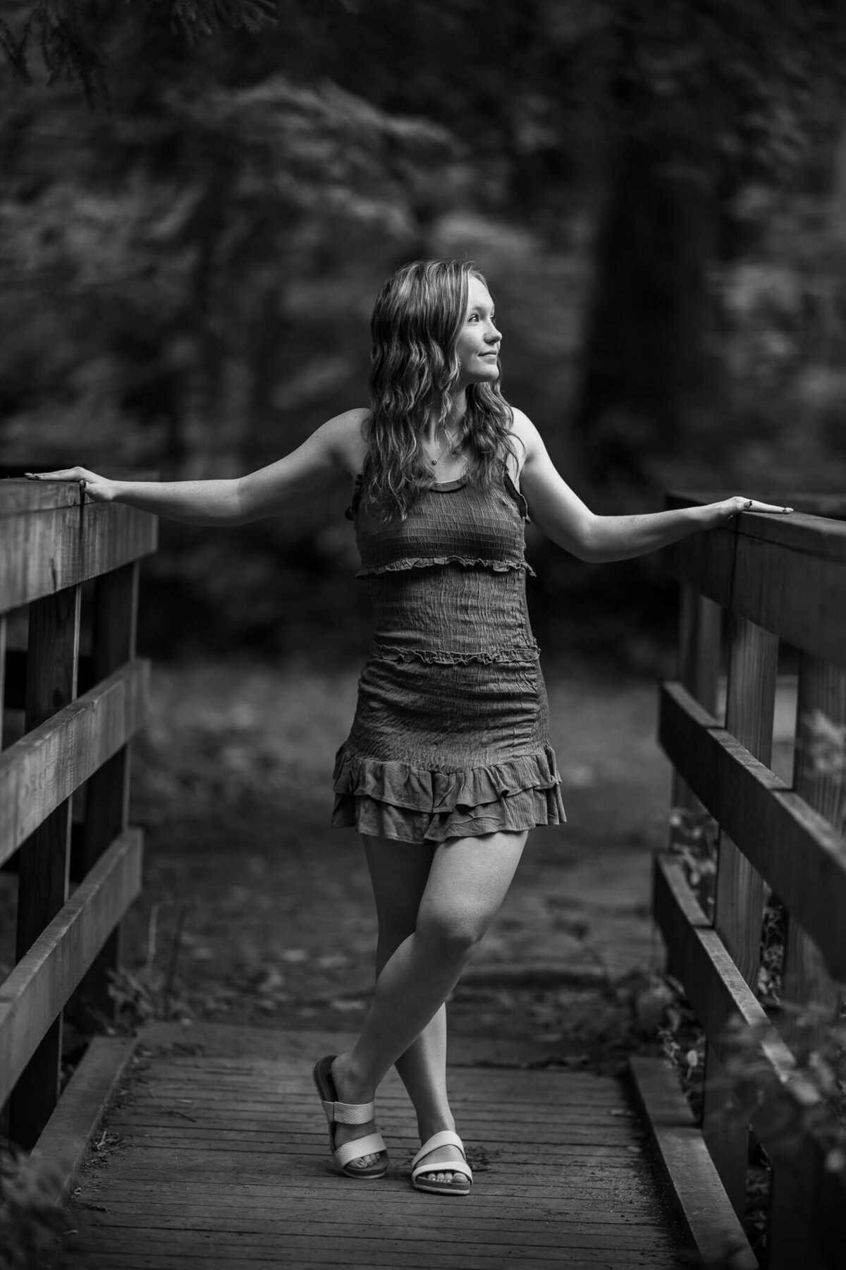 black and white senior photography of a senior standing on a bridge and looking off camera. Captured by black and white senior photographer Michael Fricke