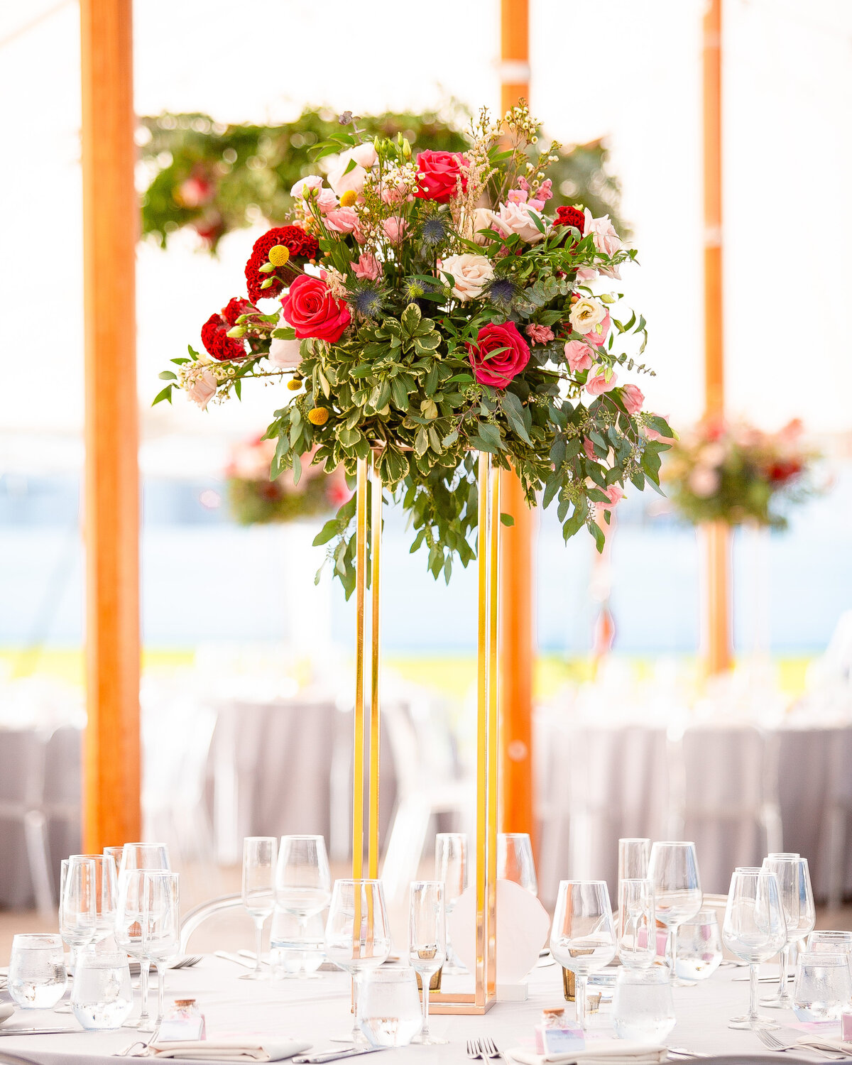 Tall flower centerpiece during tented wedding reception.