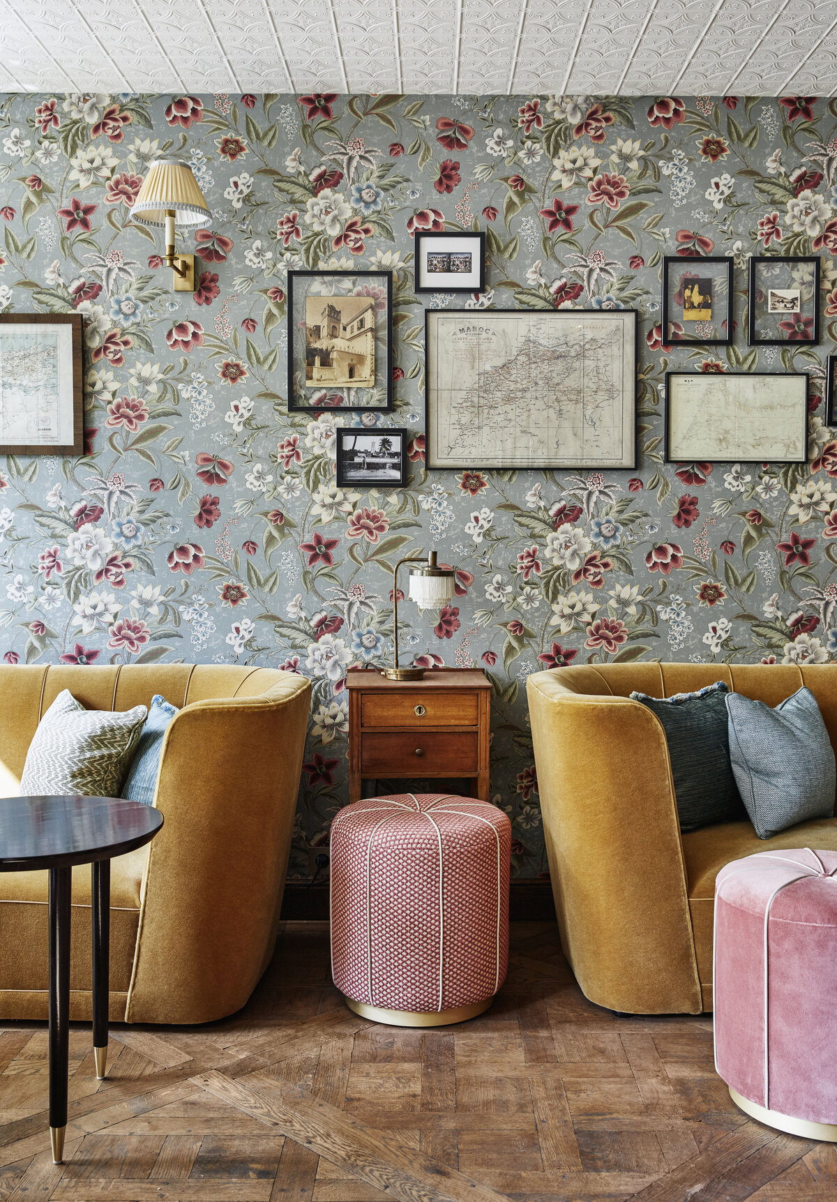 Wooden inlaid floor, floral wallpaper, white tin ceiling, yellow mohair curved sofas and pink pouffes