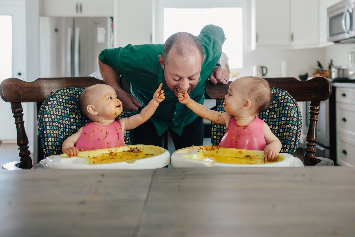 Two twins feed their father spaghetti