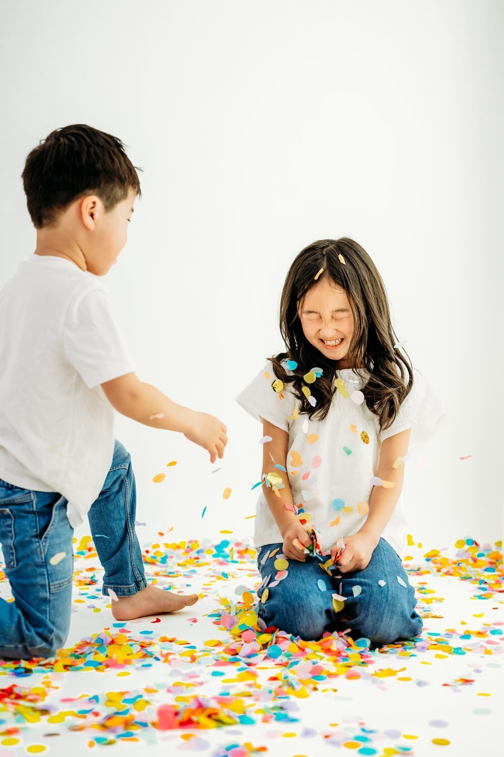 brother throws rainbow confetti at big sister