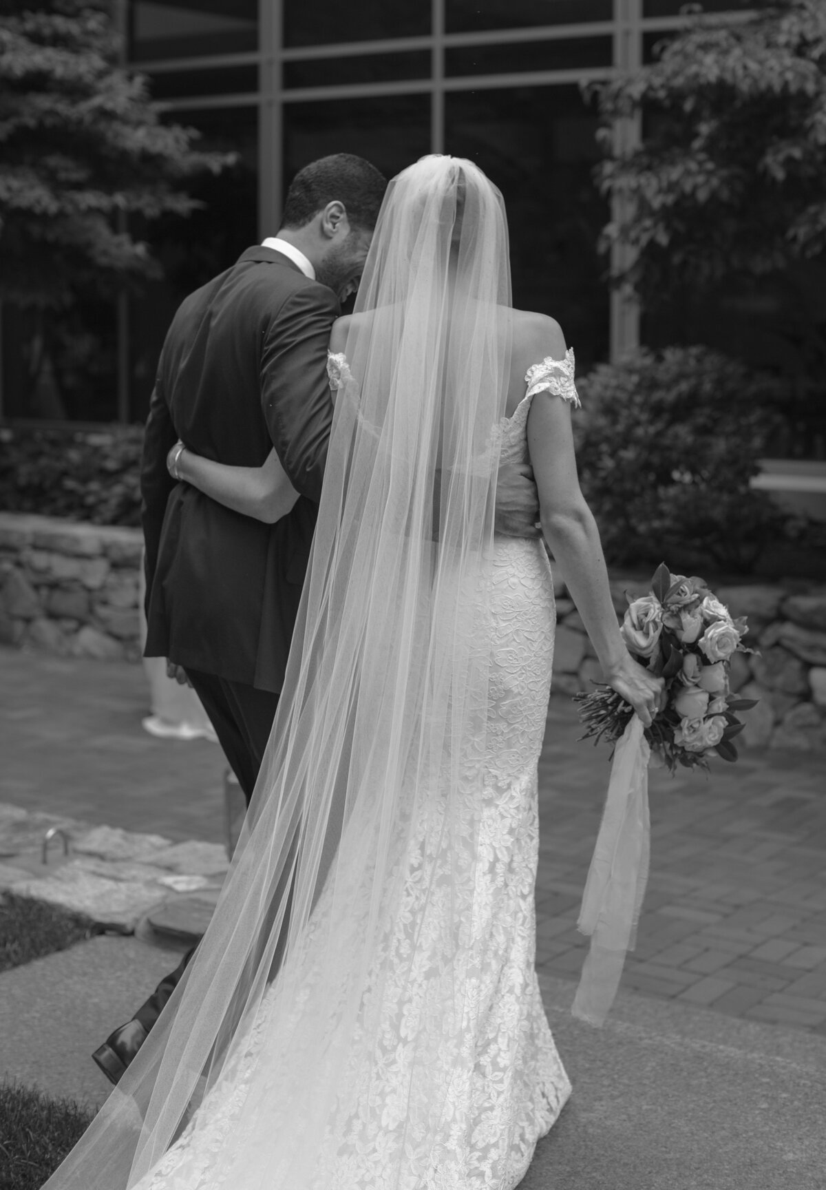 Bride and Groom walk away embracing after Boston wedding ceremony.