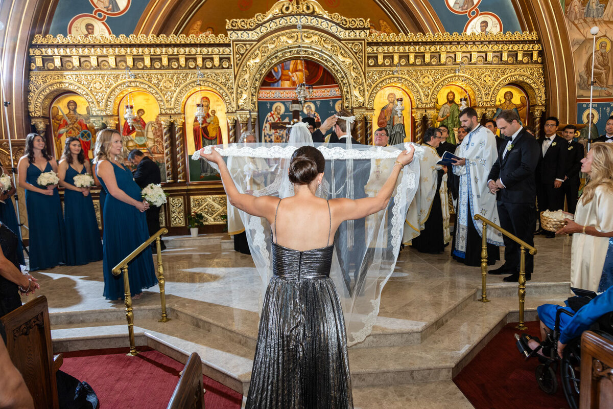 A woman in a black dress is holding a veil in a church