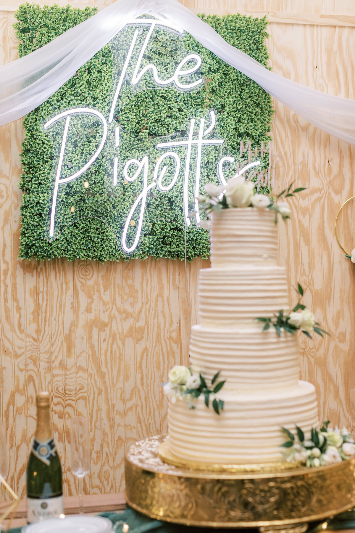 A name sign hangs on the wall behind the wedding cake.
